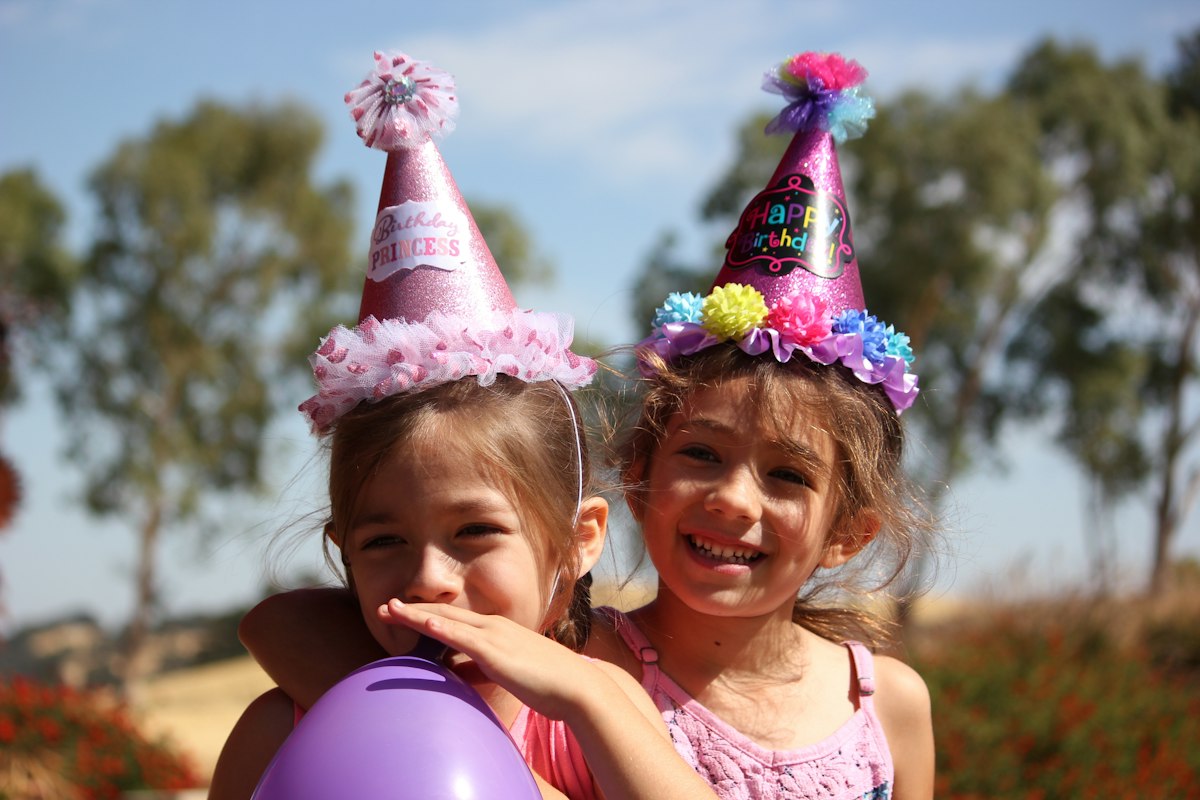 Due bambine con i cappellini di compleanno